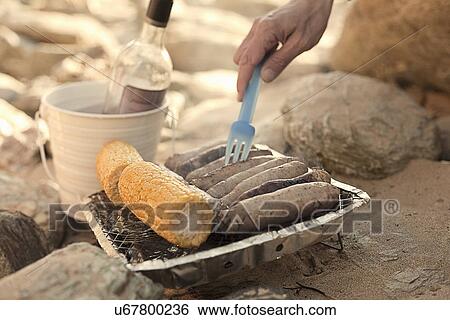 Stock Photograph - Barbecue cooking sausages and corn on the cob. Fotosearch