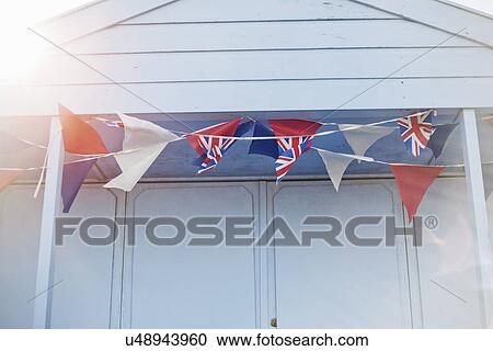 Stock Image - Blue beach hut with union jack bunting, Southwold, Sussex, UK. Fotosearch