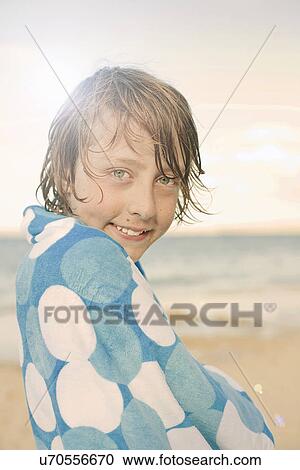 Stock Image - Boy on beach, wrapped in towel. Fotosearch