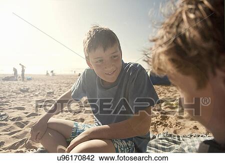 Stock Image - Boys sitting on beach. Fotosearch