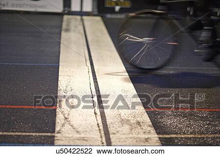 Stock Image - Close up of cyclist racing over finishing line at velodrome. Fotosearch