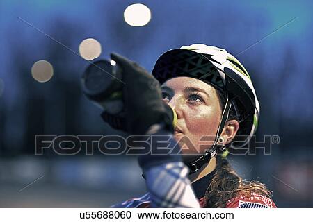 Stock Image - Close up of female cyclist drinking from water bottle. Fotosearch