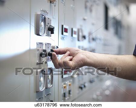 Stock Photograph - Close up of hand adjusting control in nuclear power station control room simulator. Fotosearch