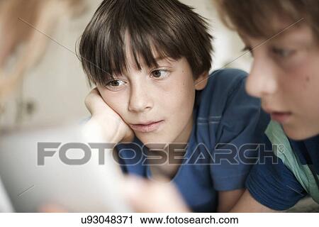 Stock Image - Close up of two brothers engrossed by digital tablet. Fotosearch