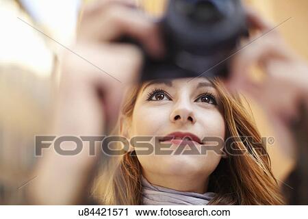 Stock Image - Close up of young woman photographing with digital camera. Fotosearch