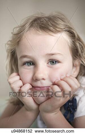 Stock Image - Close up portrait of female toddler with her chin on hands. Fotosearch