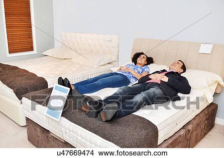 Couple lying on bed in furniture shop showroom View Large Photo Image Picture - Couple lying on bed in furniture shop showroom. Fotosearch