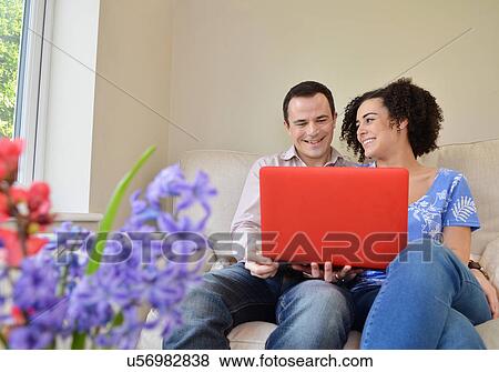 Stock Photo - Couple relaxing on sofa with laptop. Fotosearch