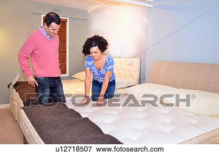 Stock Photo - Couple testing beds in furniture shop showroom. Fotosearch