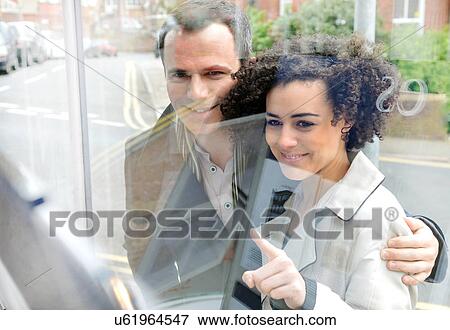 Couple window shopping, young woman pointing View Large Photo Image Stock Photo - Couple window shopping, young woman pointing. Fotosearch