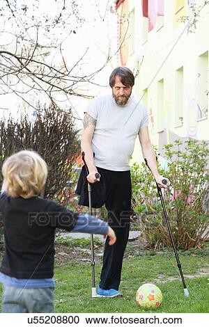 Stock Image - Disabled father with son playing football. Fotosearch