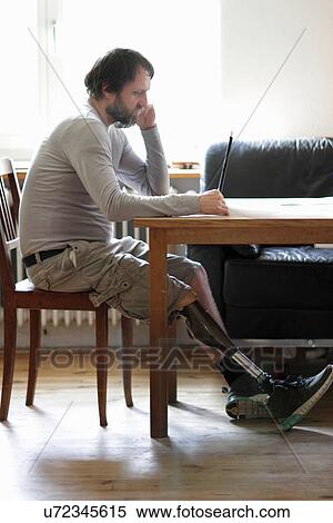 Disabled man using laptop in living room View Large Photo Image Stock Photography - Disabled man using laptop in living room. Fotosearch