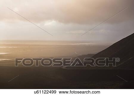 Stock Photo - Distant view of winding road in hazy landscape, Reykjanes, Iceland. Fotosearch