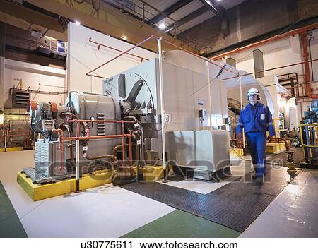 Stock Image - Engineer in generator room of power station. Fotosearch