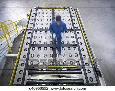 Stock Image - Engineer inspects baggage handling truck in truck repair factory. Fotosearch