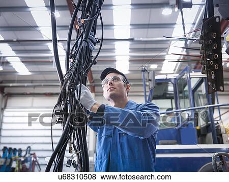 Stock Photo - Engineer installing new electrics in truck repair factory. Fotosearch