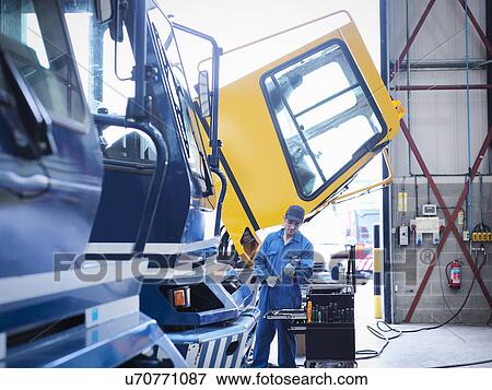 Engineer working on engine in truck repair factory View Large Photo Image Stock Photo - Engineer working on engine in truck repair factory. Fotosearch