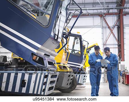 Engineers check details on digital tablet in truck repair factory View Large Photo Image Picture - Engineers check details on digital tablet in truck repair factory. Fotosearch