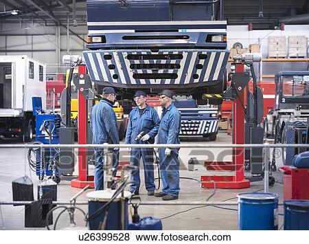 Stock Photo - Engineers in discussion in truck repair factory. Fotosearch