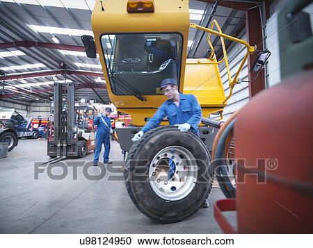 Stock Image - Engineers preparing to fix wheel in truck repair factory. Fotosearch
