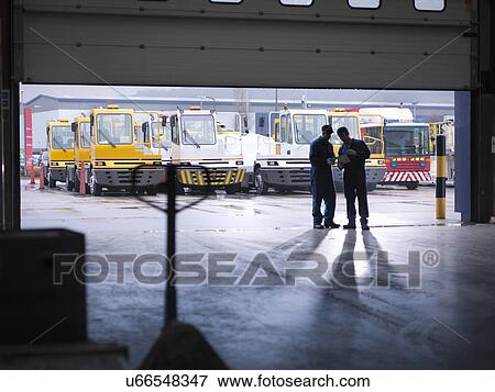 Stock Photo - Engineers silhouetted in doorway in truck repair factory. Fotosearch