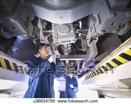 Stock Photography - Engineers underneath truck in repair factory. Fotosearch