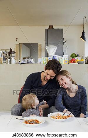 Stock Photograph - Family with baby girl eating spaghetti meal. Fotosearch