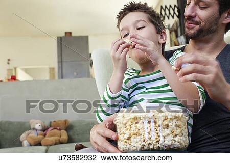 Father and son sharing popcorn in sitting room View Large Photo Image Stock Image - Father and son sharing popcorn in sitting room. Fotosearch