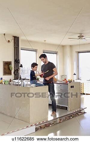 Stock Photography - Father and son with toy airplane in kitchen. Fotosearch