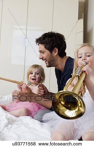 Stock Photo - Father and two young daughters playing music. Fotosearch