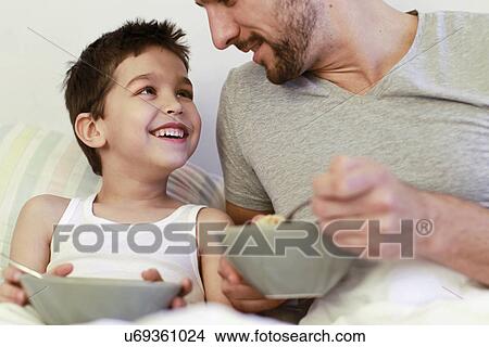Father and young son having breakfast in bed View Large Photo Image Picture - Father and young son having breakfast in bed. Fotosearch