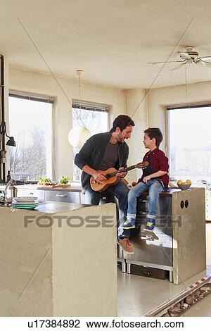 Father and young son playing guitar in kitchen View Large Photo Image Stock Image - Father and young son playing guitar in kitchen. Fotosearch
