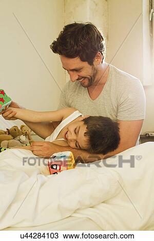 Father and young son playing on bed View Large Photo Image Stock Image - Father and young son playing on bed. Fotosearch