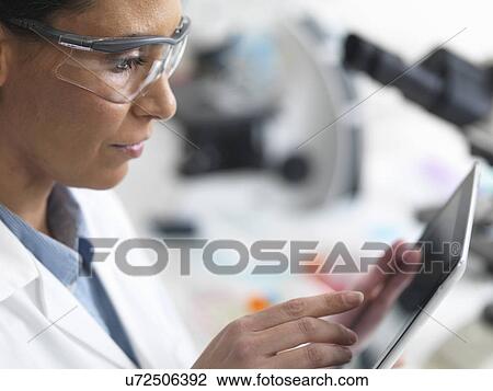 Stock Image - Female scientist viewing test results on a digital tablet in lab. Fotosearch