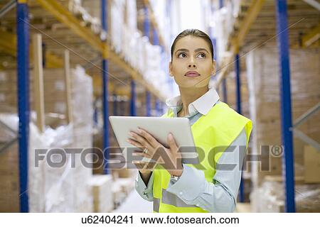 Female warehouse worker using digital tablet View Large Photo Image Stock Image - Female warehouse worker using digital tablet. Fotosearch