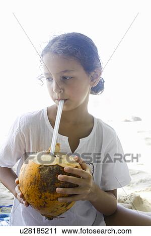 Stock Image - Girl drinking from a coconut. Fotosearch