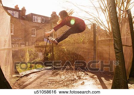 Stock Photograph - Girl mid-air in trampoline. Fotosearch