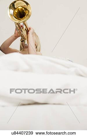 Stock Photo - Girl playing trumpet in bed. Fotosearch