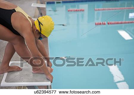 Stock Photo - Girl training and preparing to jump into swimming pool. Fotosearch