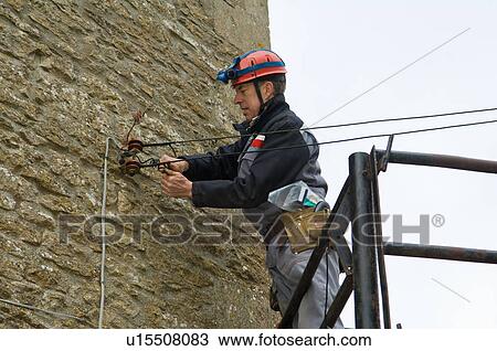 Stock Image - Male electrician on platform fixing house electricity supply. Fotosearch