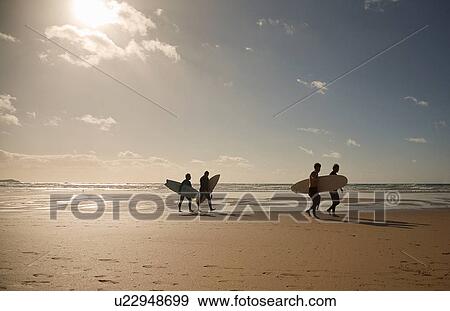 Stock Photo - Mature adults carrying surfboards. Fotosearch