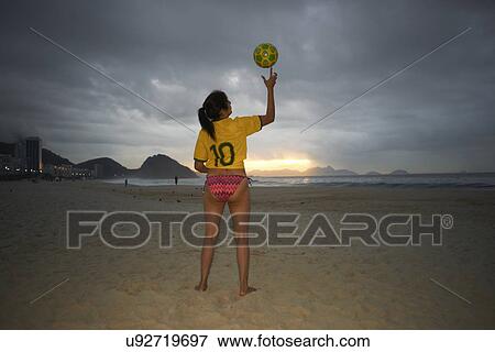 Stock Photo - Mature woman balancing soccer ball on finger, Copacabana beach, Rio De Janeiro, Brazil. Fotosearch