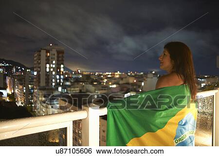 Stock Photograph - Mature woman gazing from balcony at night, Rio De Janeiro, Brazil. Fotosearch