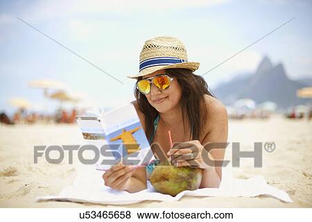 Stock Photo - Mature woman reading tourist guide, Ipanema beach, Rio De Janeiro, Brazil. Fotosearch