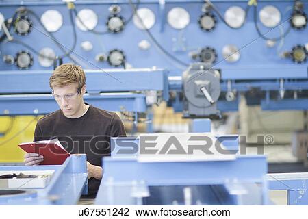 Mid adult male technician checking paperwork in engineering plant View Large Photo Image Stock Image - Mid adult male technician checking paperwork in engineering plant. Fotosearch