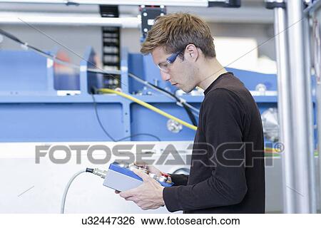 Mid adult male technician monitoring machines in engineering plant View Large Photo Image Stock Photograph - Mid adult male technician monitoring machines in engineering plant. Fotosearch