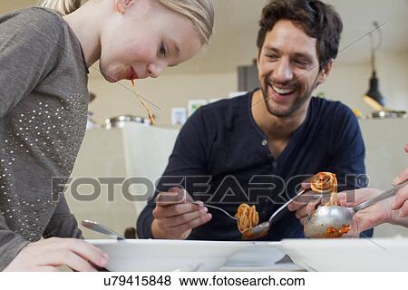 Mid adult man and family eating a spaghetti meal View Large Photo Image Stock Photo - Mid adult man and family eating a spaghetti meal. Fotosearch