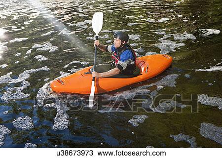 Stock Image - Mid adult man kayaking on peaceful river. Fotosearch