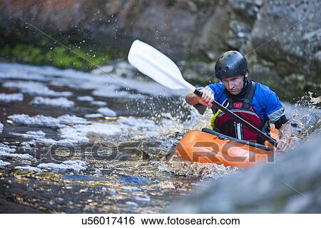 Stock Photograph - Mid adult man kayaking on river rapids. Fotosearch