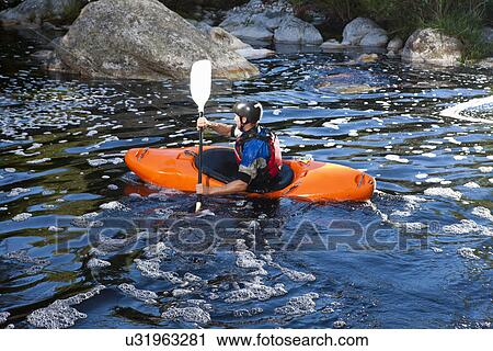 Stock Image - Mid adult man kayaking on river. Fotosearch